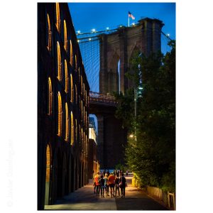 A group walking towards the Brooklyn Bridge on a warm summer night.