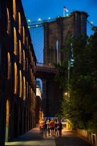 A group walking towards the Brooklyn Bridge on a warm summer night.